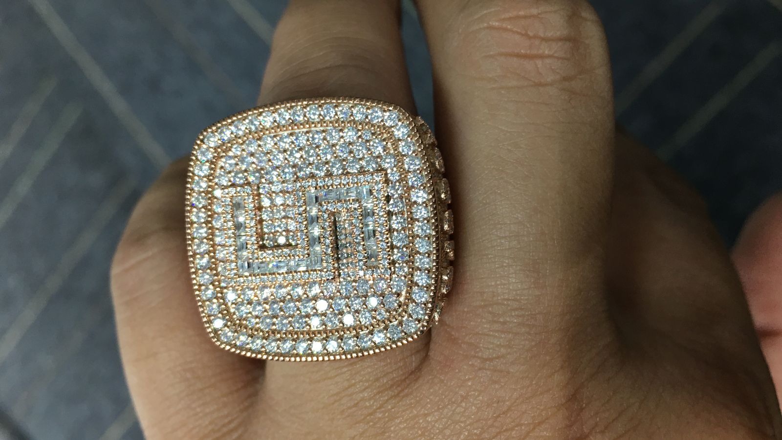Fully iced moissanite ring worn on a finger, densely hand-set stones catching daylight